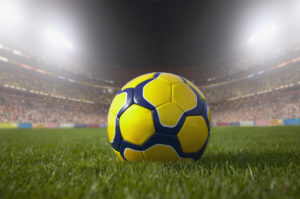 Soccer ball resting on grass in large stadium